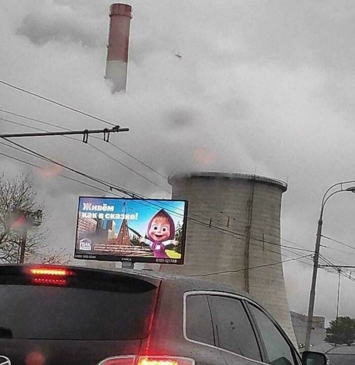 Pollution from factory smokestacks emitting smoke behind city billboard