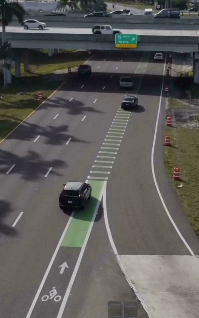 Car misusing bike lane at highway exit in a suburban hell traffic scene
