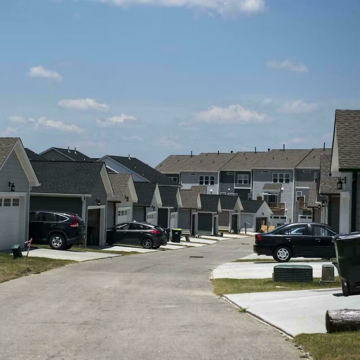 Suburban hell neighborhood with identical houses and cars parked in driveways