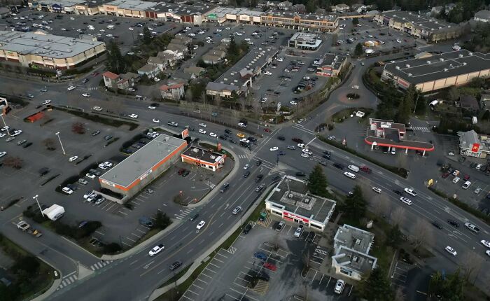 Aerial view of suburban hell showing parking lots and busy roads with scattered buildings