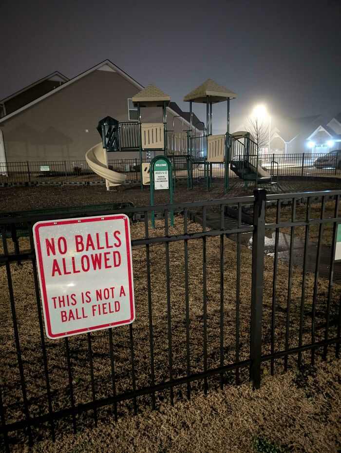 Playground behind a fence with a no balls allowed sign in suburban hell