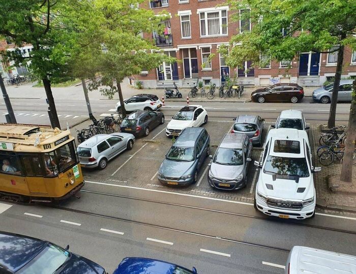 Street view of parked cars blocking tram tracks in suburban area