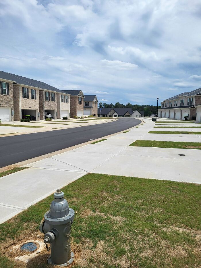 Empty suburban street with identical houses and fire hydrant in foreground