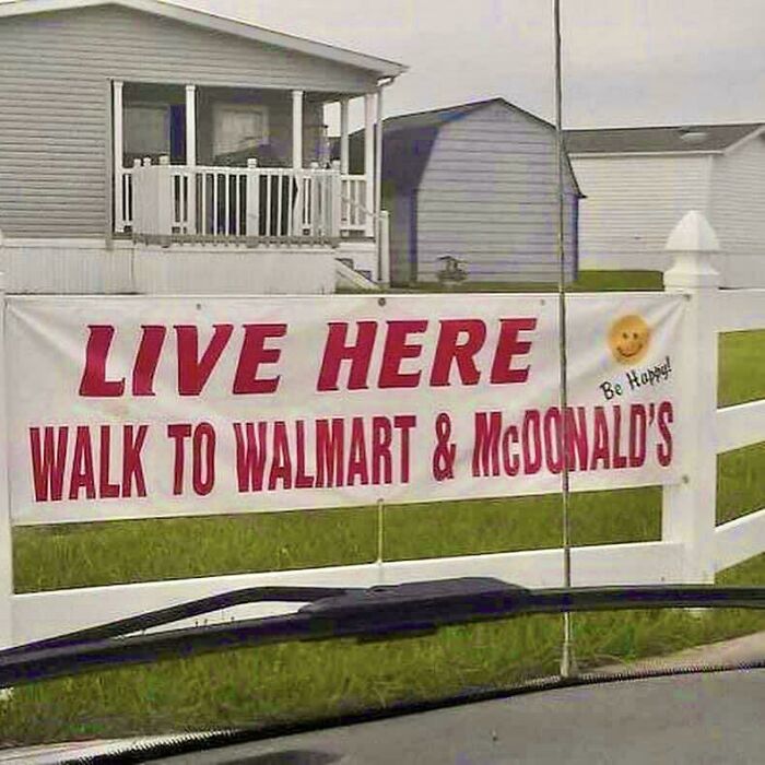Banner on a fence in a suburban neighborhood advertising walkability to Walmart and McDonald's