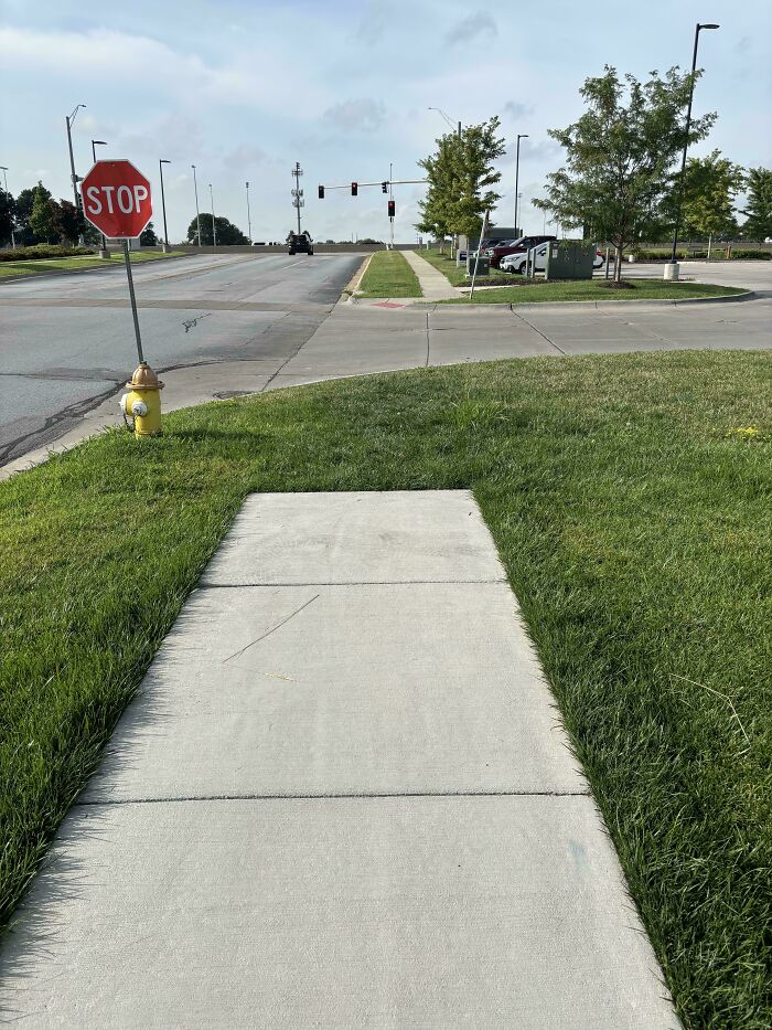 Sidewalk in suburb abruptly ending before a busy intersection in suburban hell
