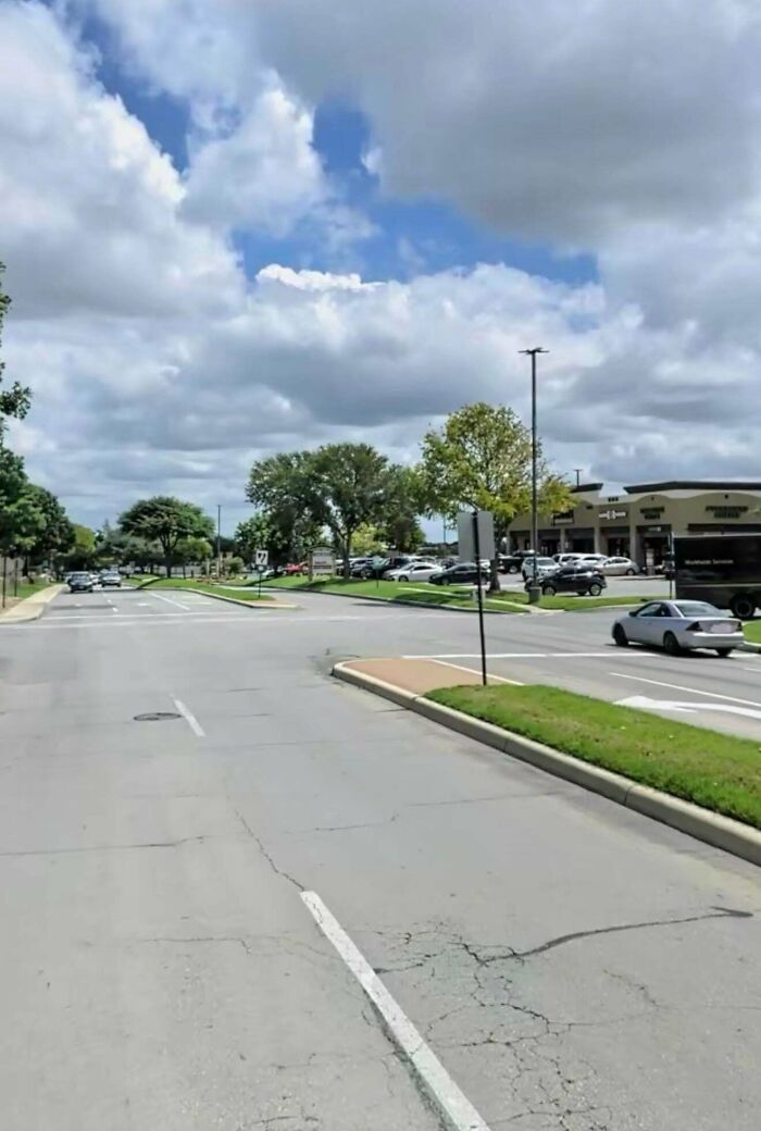 Suburban street with wide roads and parked cars near shopping center