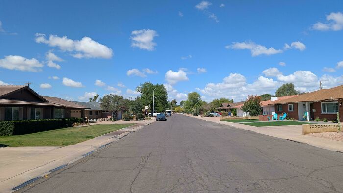 Quiet suburban residential street with single-story houses under blue sky
