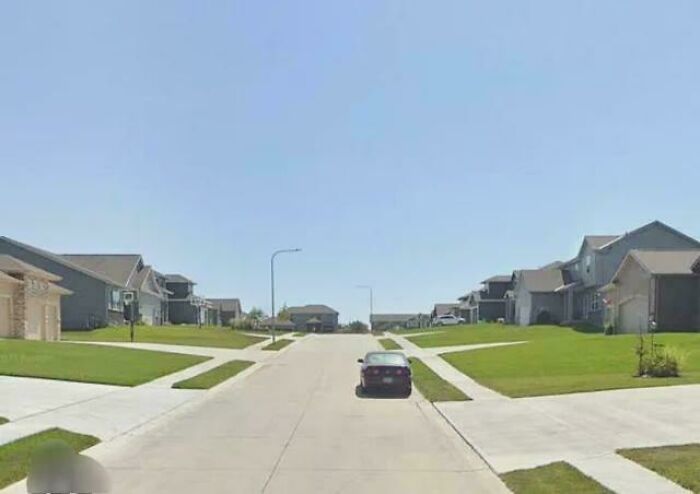 Suburban street with identical houses and a single car parked on road