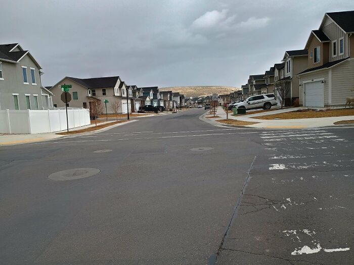 Empty suburban street with houses on both sides under cloudy sky