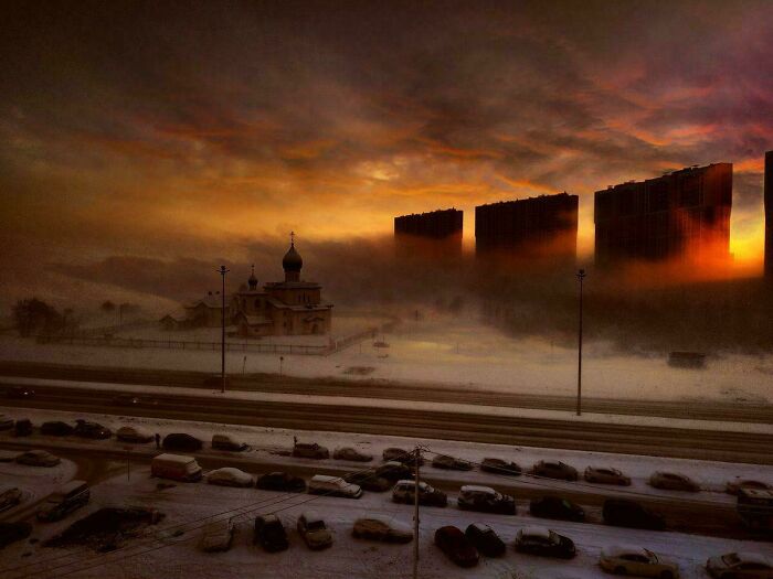 Sunset over city with heavy fog and silhouettes of tall buildings in urban environment
