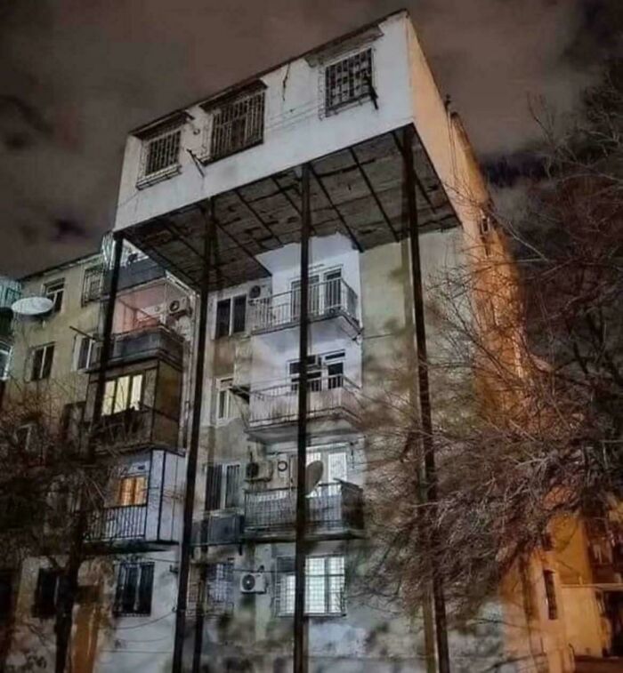 Unusual urban building with upper floors supported by tall metal pillars