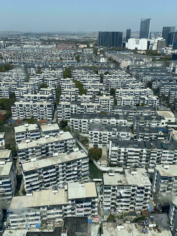 Overhead view of densely packed urban buildings with some greenery and waterways