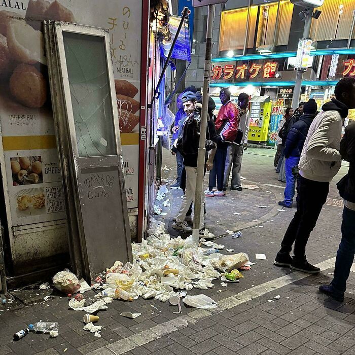 Urban hell street littered with trash and people at night