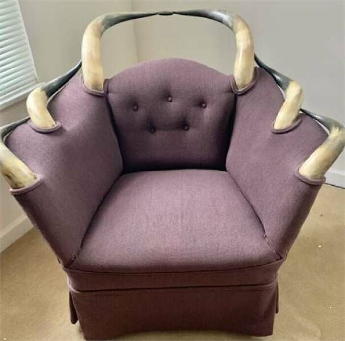 An unconventional purple upholstered armchair featuring large, curved animal horns as armrests, a daring interior designer pick.