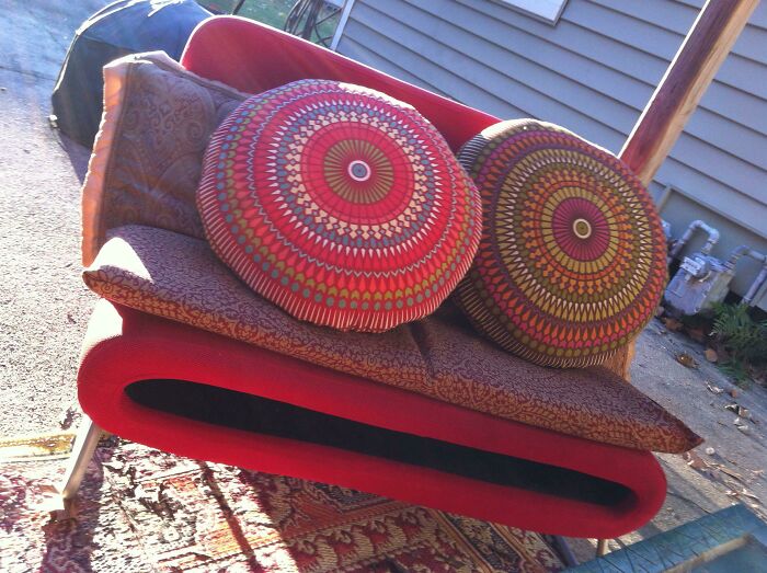 An artistic red couch adorned with two patterned circular pillows, a creative piece for an interior designer.