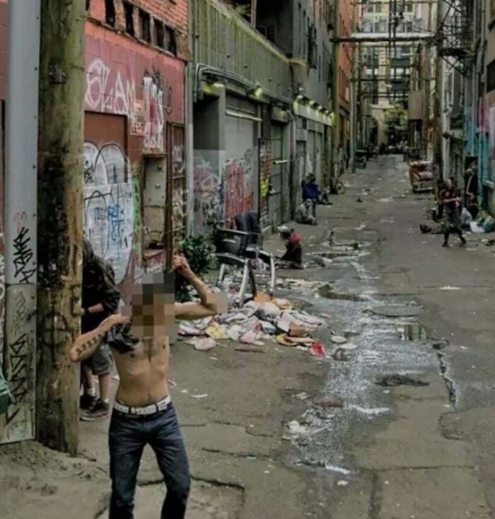 Graffiti-covered urban alley with garbage and people