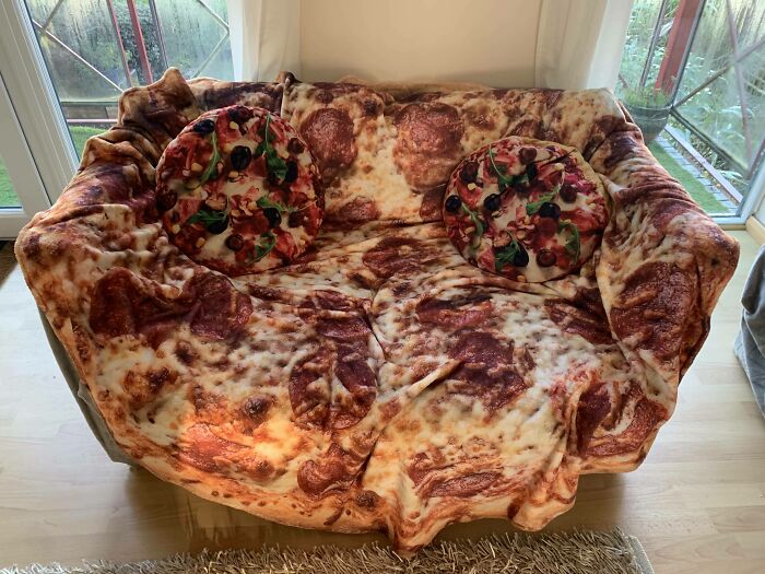 A cozy couch designed with a realistic pizza print, complete with matching round pizza pillows, an interior designer's delight.