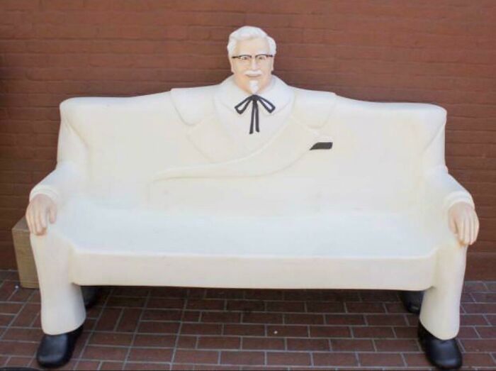 A white couch shaped like Colonel Sanders in his iconic white suit, a memorable interior designer piece.