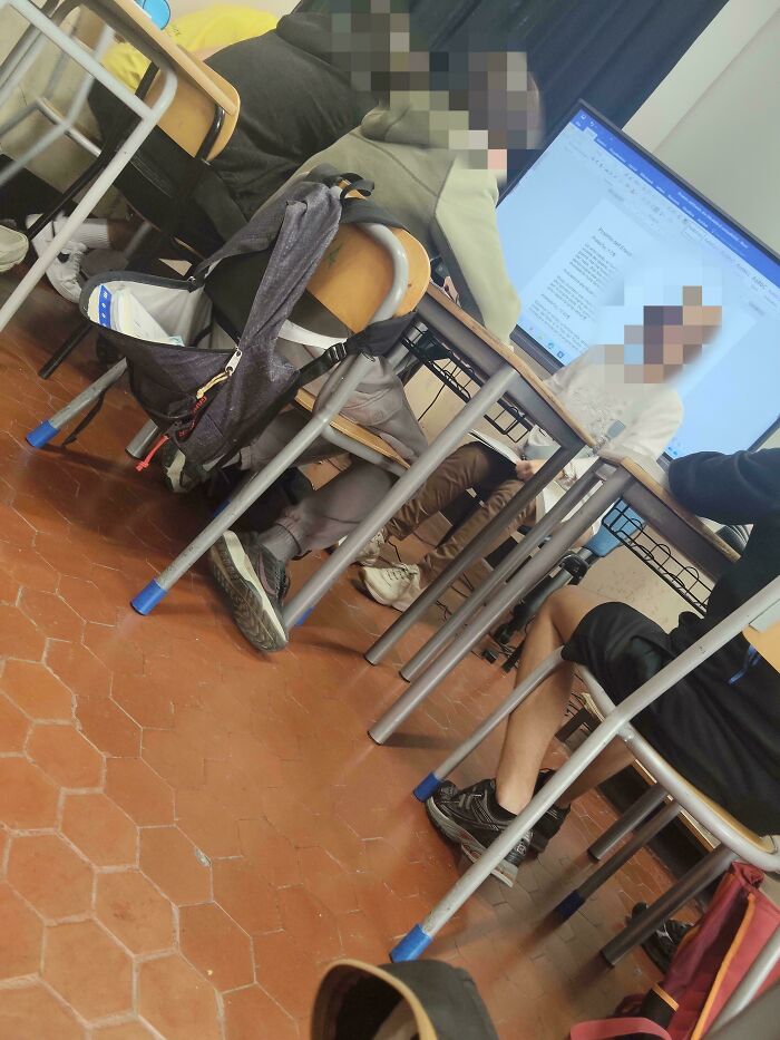 A classroom with students at desks, some looking at a computer screen, possibly engaged in learning activities with their teachers.