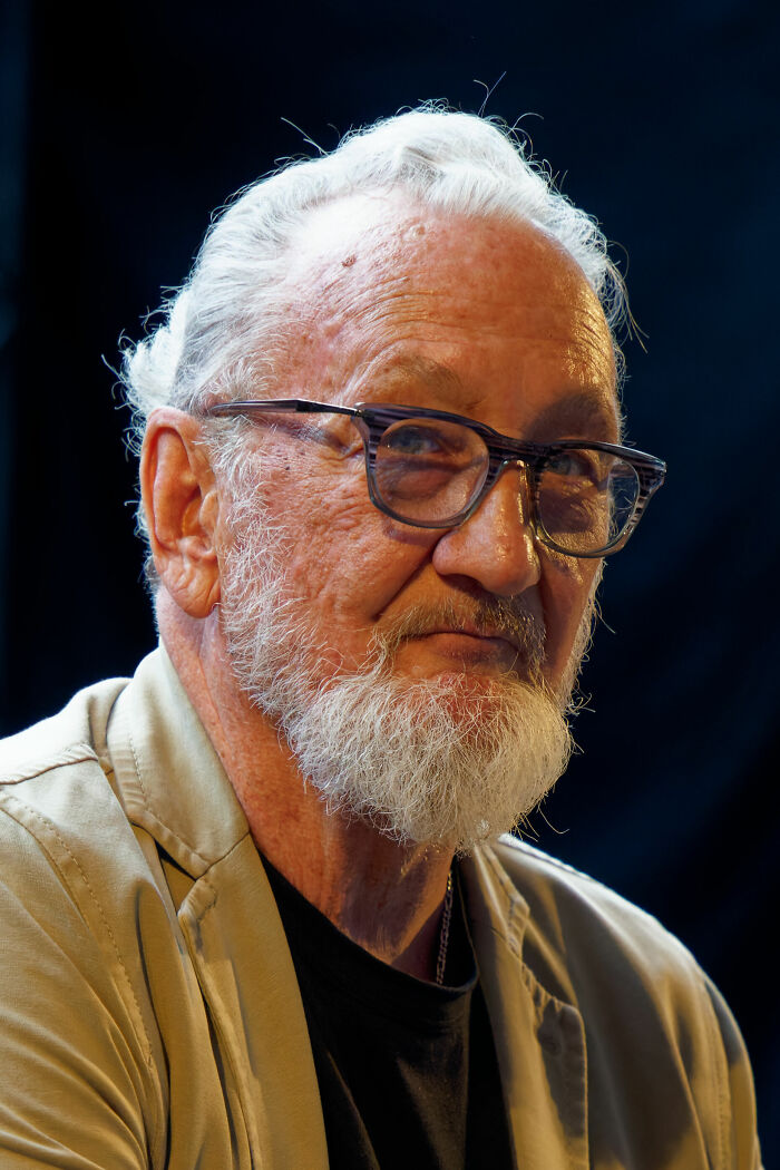 Close-up portrait of Robert Englund with glasses and white beard, highlighting his acting career