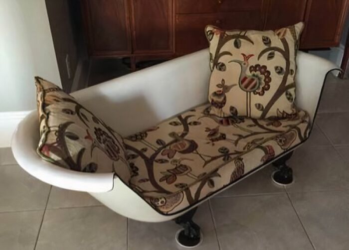 A unique couch made from a repurposed white bathtub with patterned cushions, an interior designer's unusual choice.