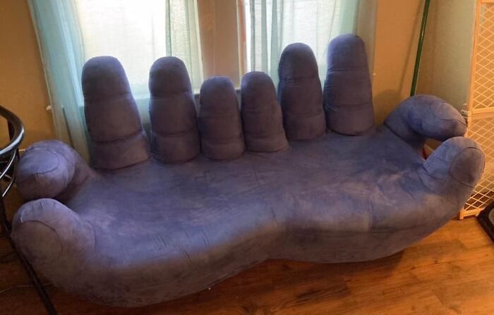 An unconventional, hand-shaped couch in a soft purple hue, a bold choice for any interior designer.