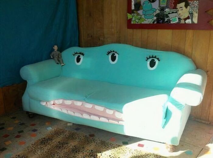 A vibrant teal couch with cartoon eyes and a large open mouth, showcasing creative interior design.