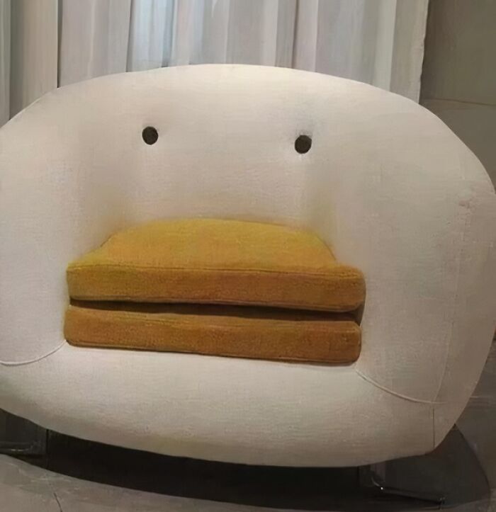 A whimsical white and yellow couch with two dark holes resembling eyes, a playful interior designer addition.