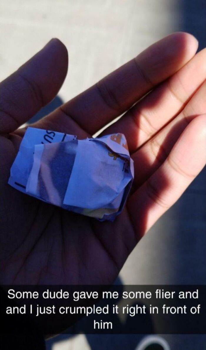 Hand holding a crumpled paper flier showing a defiant attitude