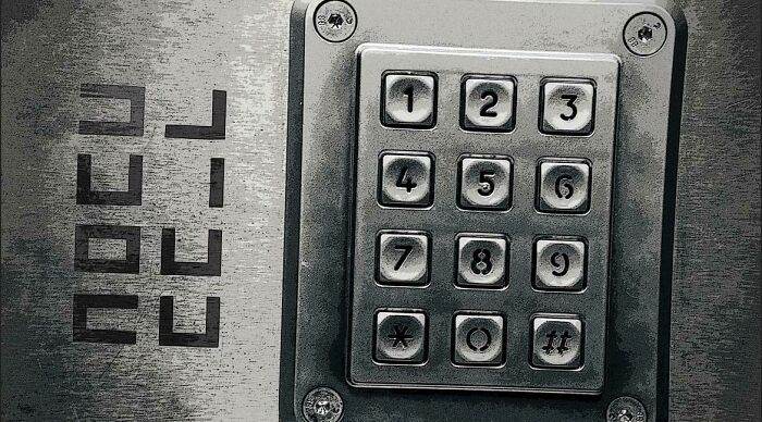A close-up of a metal keypad with numbers 1-9, *, 0, and #, next to the word CELL on a metallic surface, representing a brain puzzle.