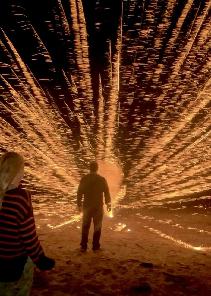 Person standing in front of sparklers exploding outward in a fireworks fail