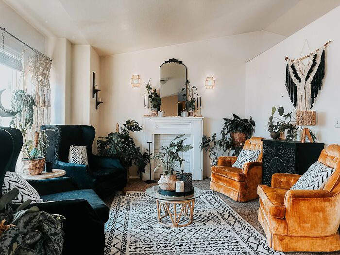 A cozy living room with a fireplace, several plants, and elegant home decor projects, including orange armchairs.
