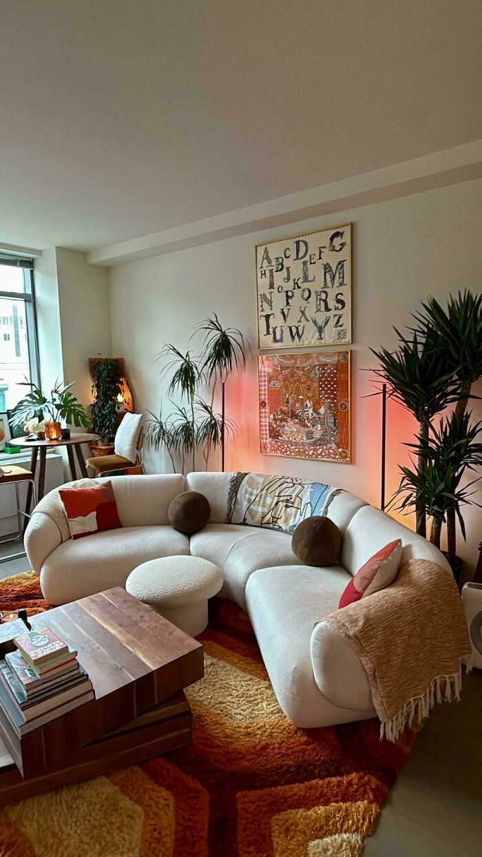 A stylish living room featuring a curved sofa, plants, and unique home decor projects with artistic wall hangings.