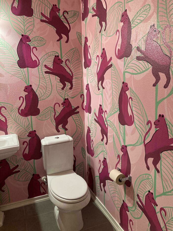 A bold home decor project featuring a small bathroom with pink cheetah print wallpaper and green leaves.