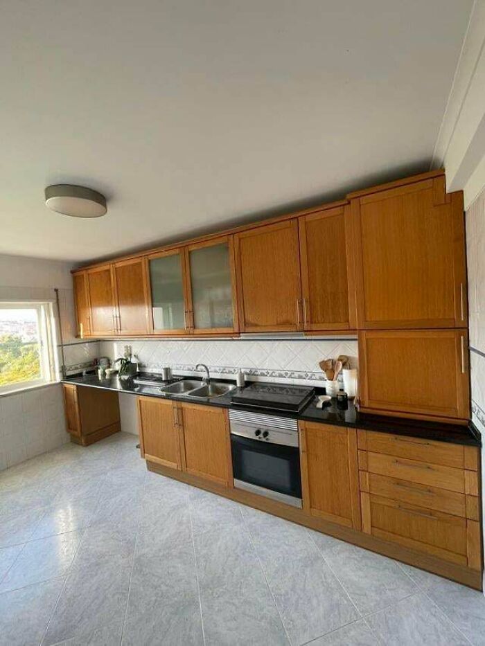 A kitchen with light wood cabinets, black countertops, and a built-in oven, ready for new home decor projects.