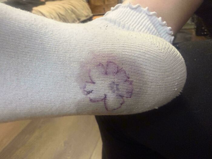 A purple flower drawn on the heel of a white sock, a mildly interesting picture detail.