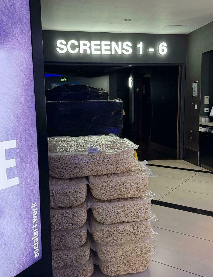 Massive bags of popcorn await moviegoers at a cinema entrance, making for a mildly interesting picture.