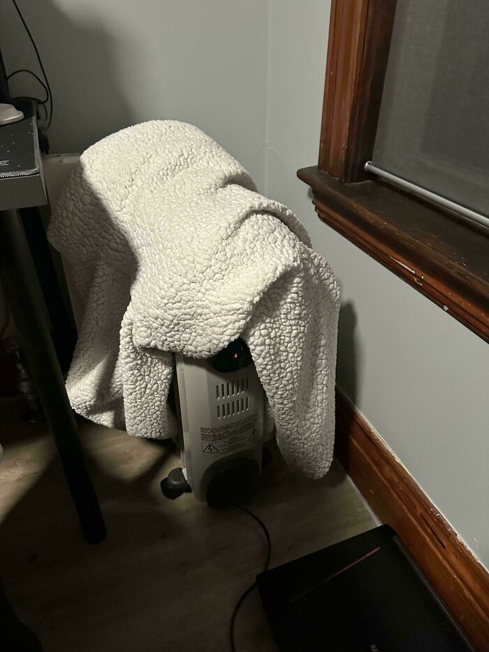 A dangerous heating unit draped with a blanket, a fire hazard and completely unnecessary.