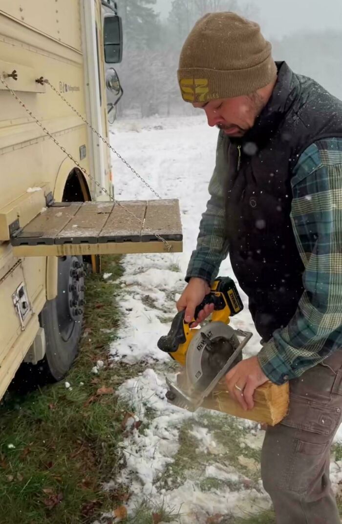 A man uses a circular saw to cut a log in the snow next to a bus, representing dangerous things people did.