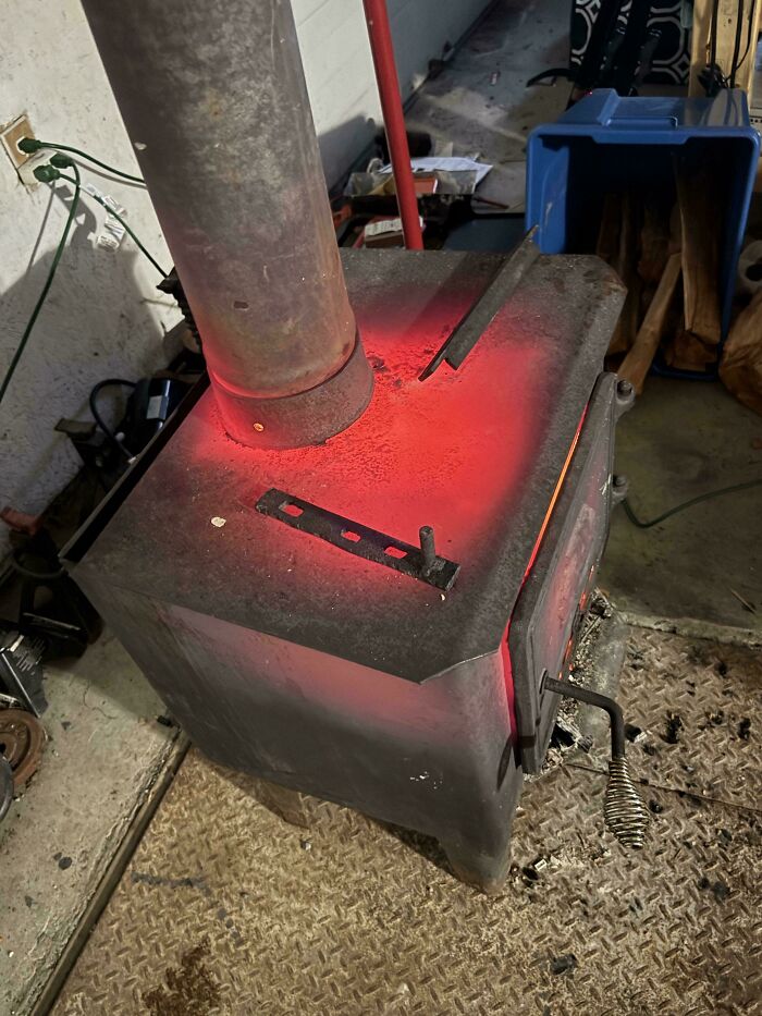 A red-hot wood-burning stove glowing in a garage, illustrating dangerous conditions.