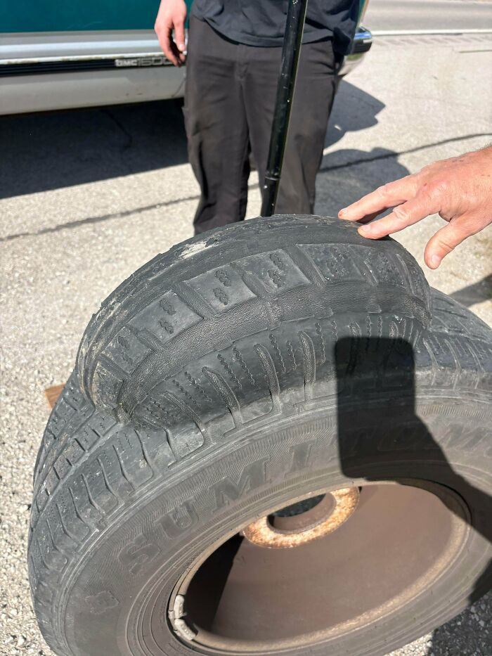 A hand points to a dangerously bulged and worn tire, one of many dangerous things people did.