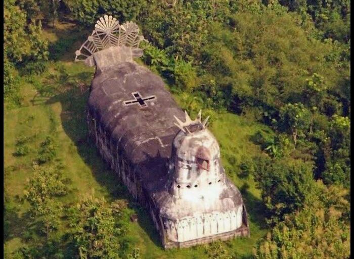Aerial view of a unique, boat-shaped building resembling a submarine in a forest, a fascinating pic and quick fact.