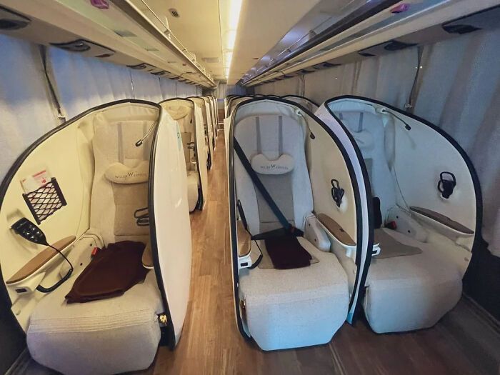 A luxurious bus interior with individual enclosed seating pods, offering a comfortable brain boost travel experience.