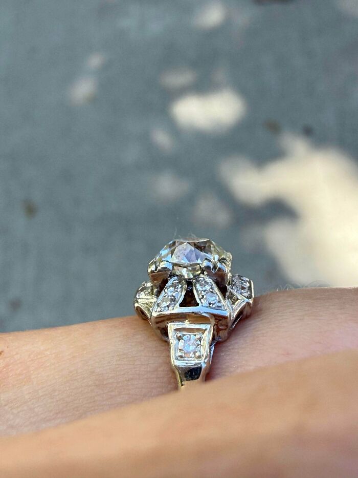 A remarkable antique diamond ring with a large center stone and smaller diamonds, worn on a finger.