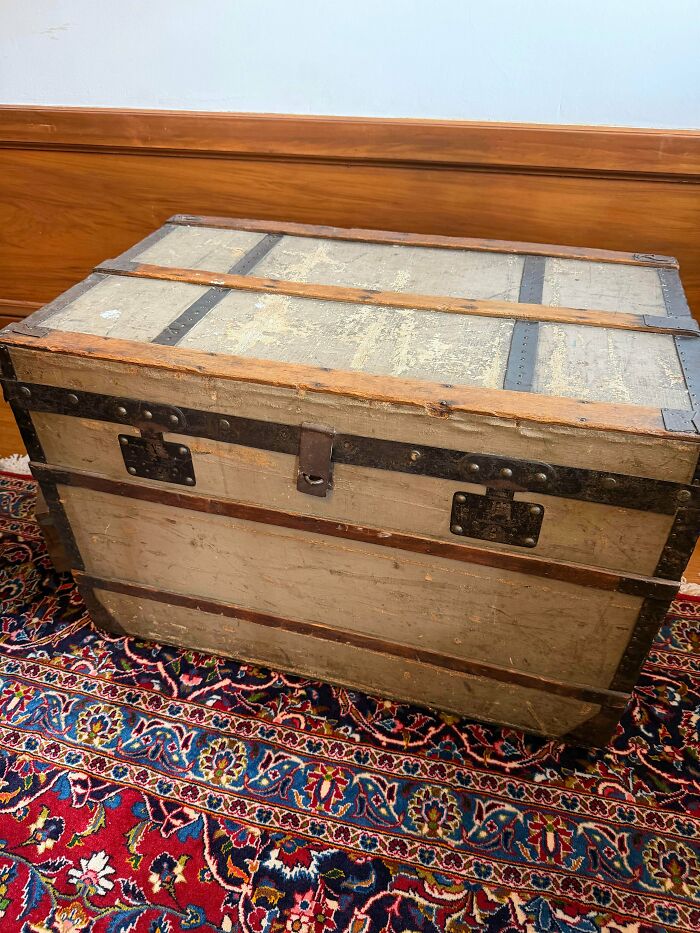 A remarkable antique wooden trunk with metal bands and a latch, resting on a colorful patterned rug.