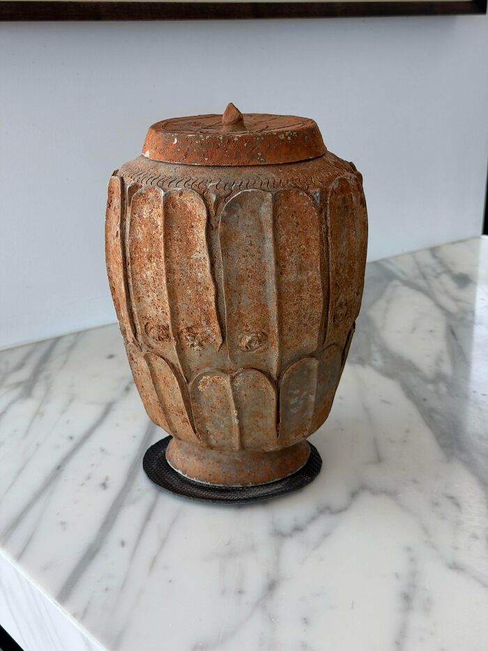 A remarkable antique terracotta vase with a textured, fluted design and a lid.