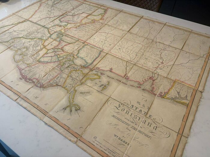 An old, remarkable antique map of Louisiana unfolded on a surface, displaying historical geographical details.