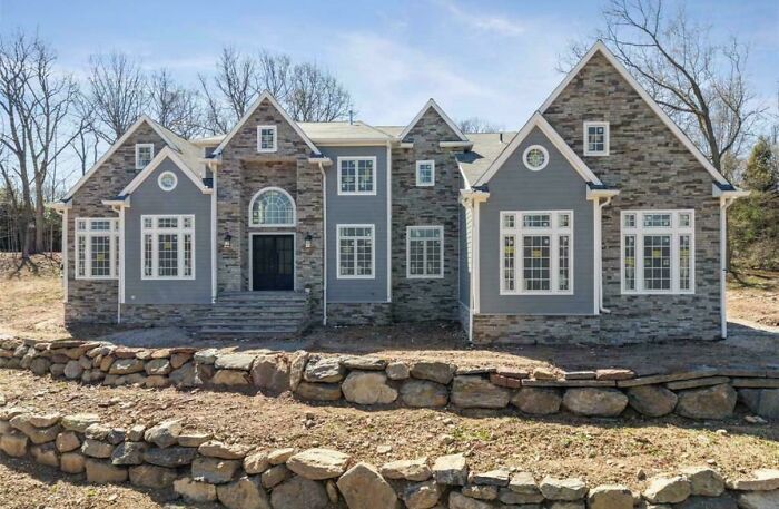 Large new construction home with stone and siding, featuring multiple gables, inspired by mansion designs.