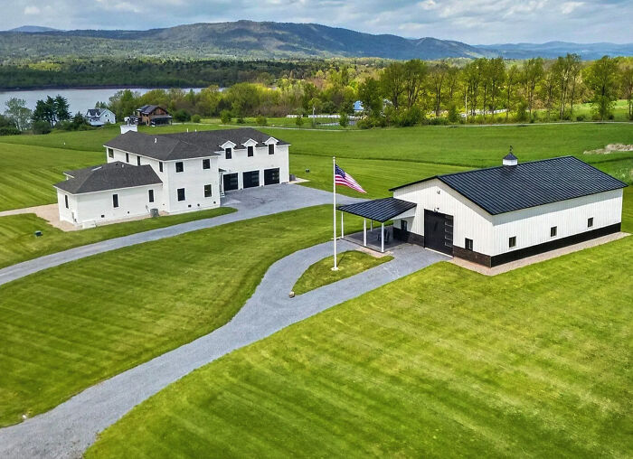 Aerial view of a white mansion and barn in a green field, showcasing mansion-inspired architecture.