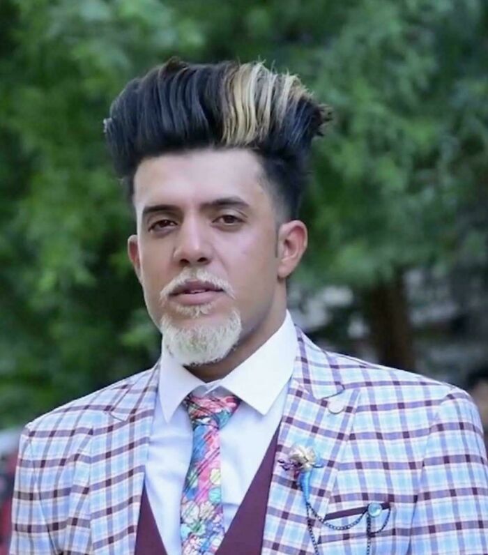A man with a tall, styled black and blonde pompadour and a white goatee, illustrating a bad hair day.